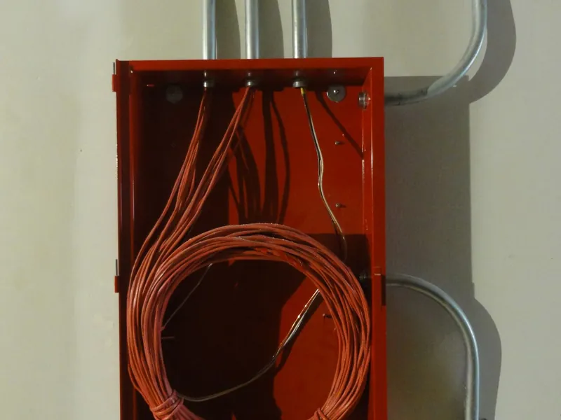 Cuadro eléctrico rojo con cable enrollado en su interior
